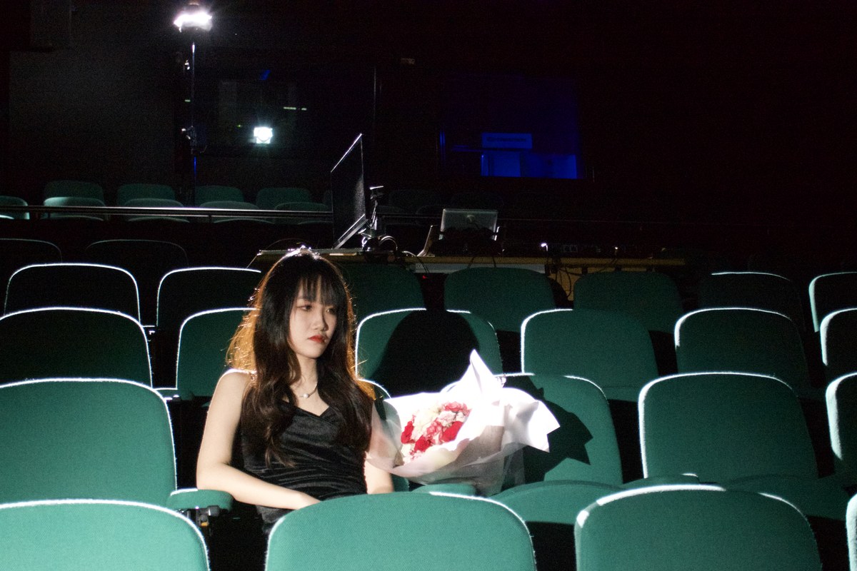 alone in the rows, bouquet beside her